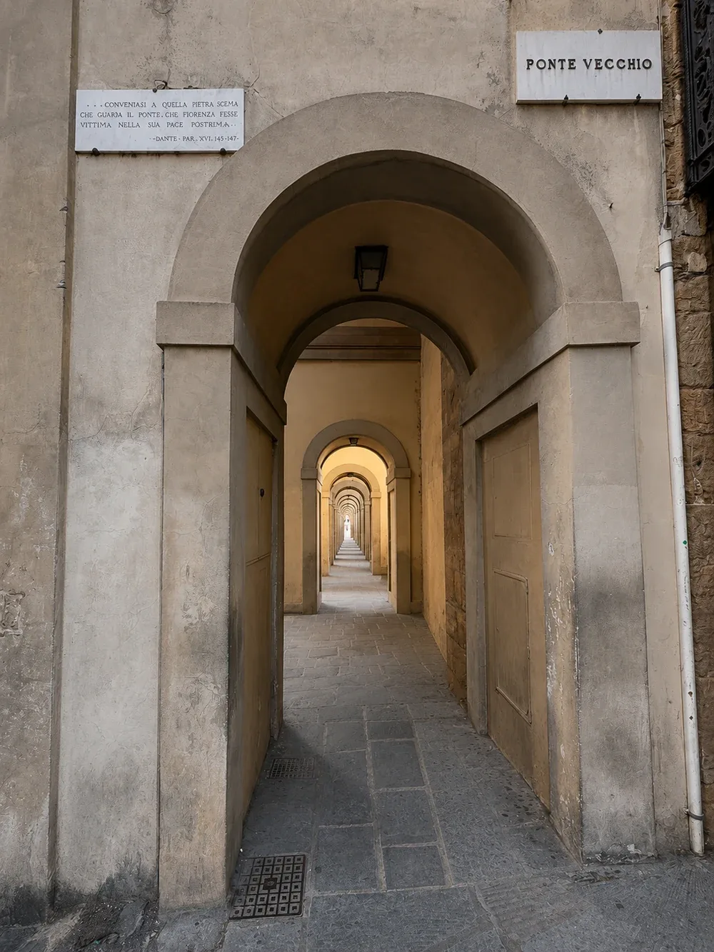 Stone archway in Florence opening onto the long vaulted passage beside the Ponte Vecchio